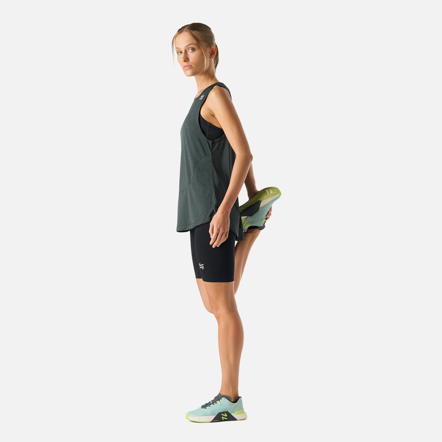 Polera Mujer Tempo Tank Top Melange Gris Vulcano en actividad física, combinada con calzas negras, muestra su versatilidad para entrenar o viajar.