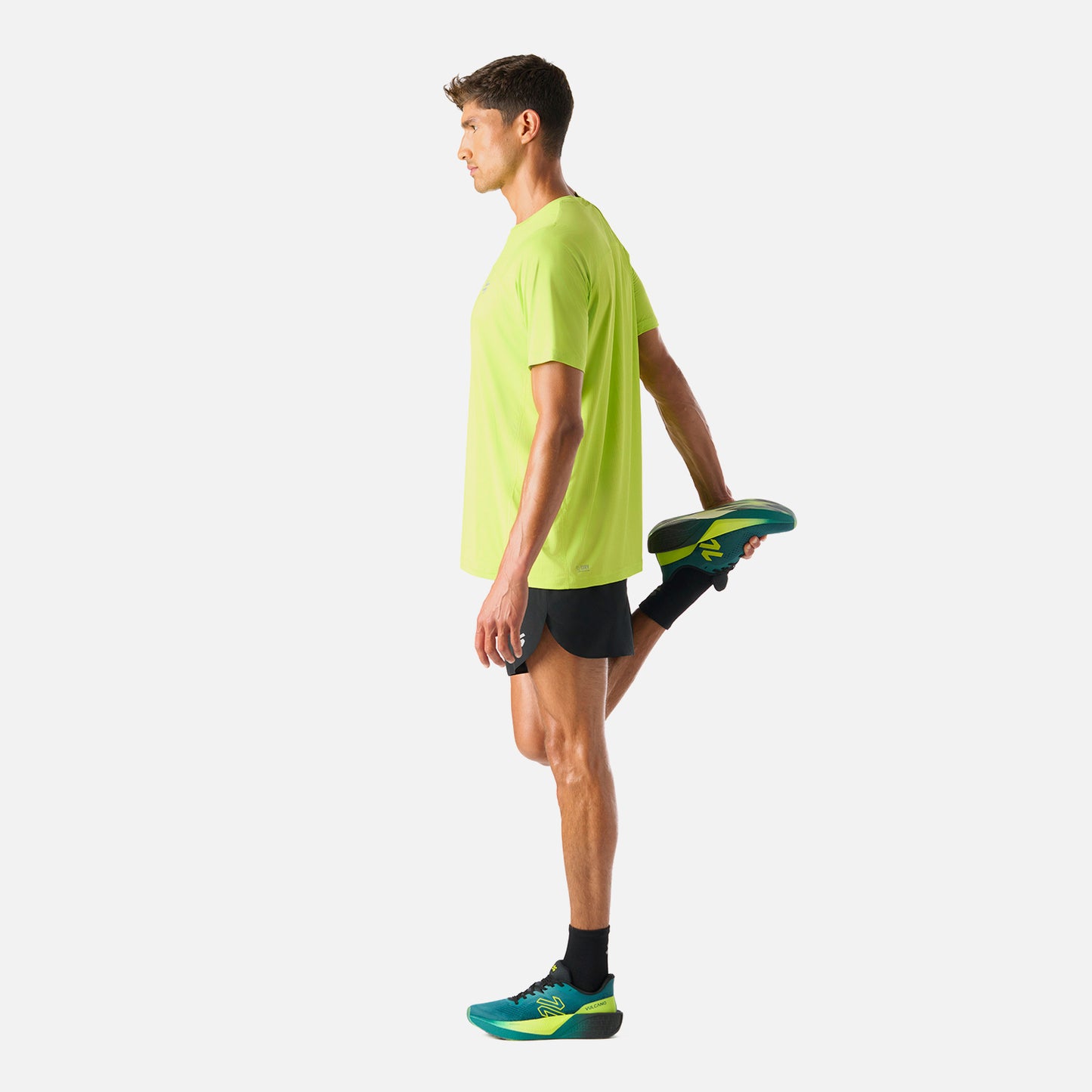 Polera Hombre Verde Lima Vulcano - Deportiva Q-Dry, en uso durante estiramiento. Prenda funcional para deportes como running o pádel.