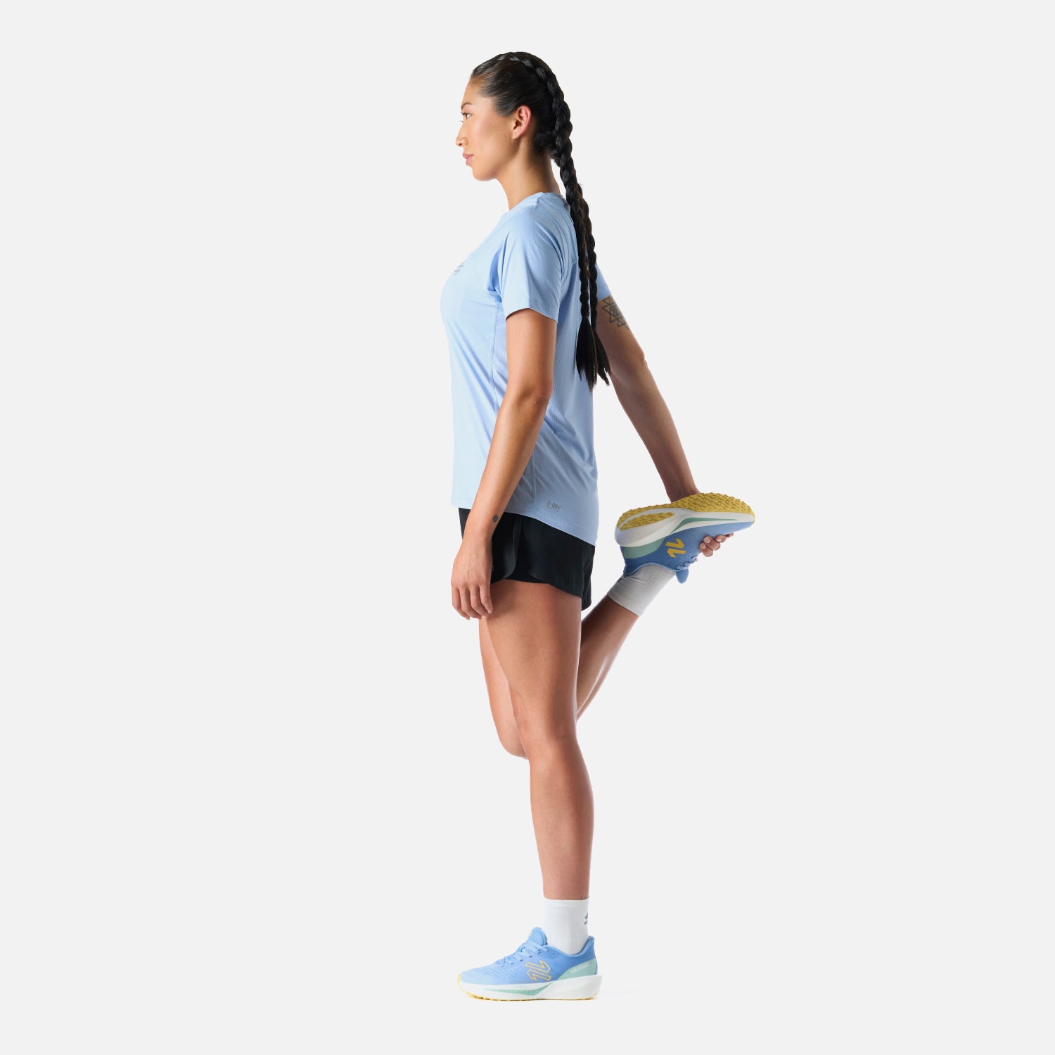 Polera Mujer Built To Move T-Shirt Celeste Vulcano en uso durante estiramiento. Tejido técnico que favorece la movilidad y frescura.