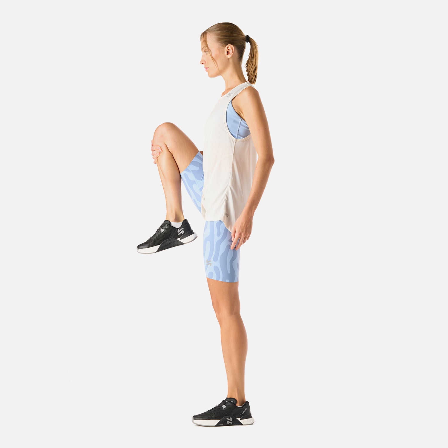 Polera Mujer Tempo Tank Top Negro Vulcano en actividad física, combinada con calzas celestes, muestra su versatilidad para entrenar o viajar.