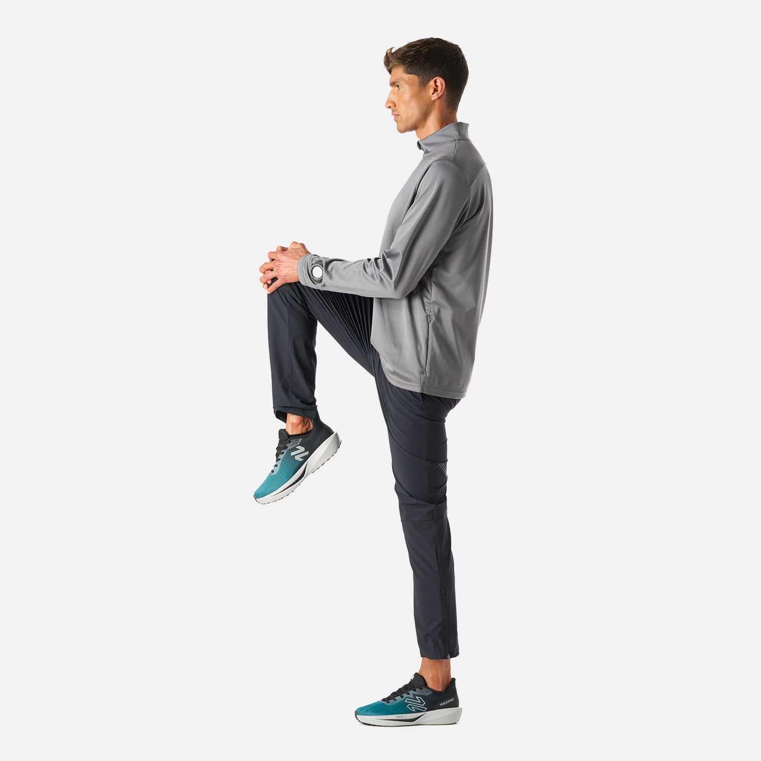 Polerón Hombre Built To Move 1/4 Zip Midlayer Gris Medio Vulcano en uso durante estiramiento, mostrando su flexibilidad y confort para deportes de alto rendimiento.