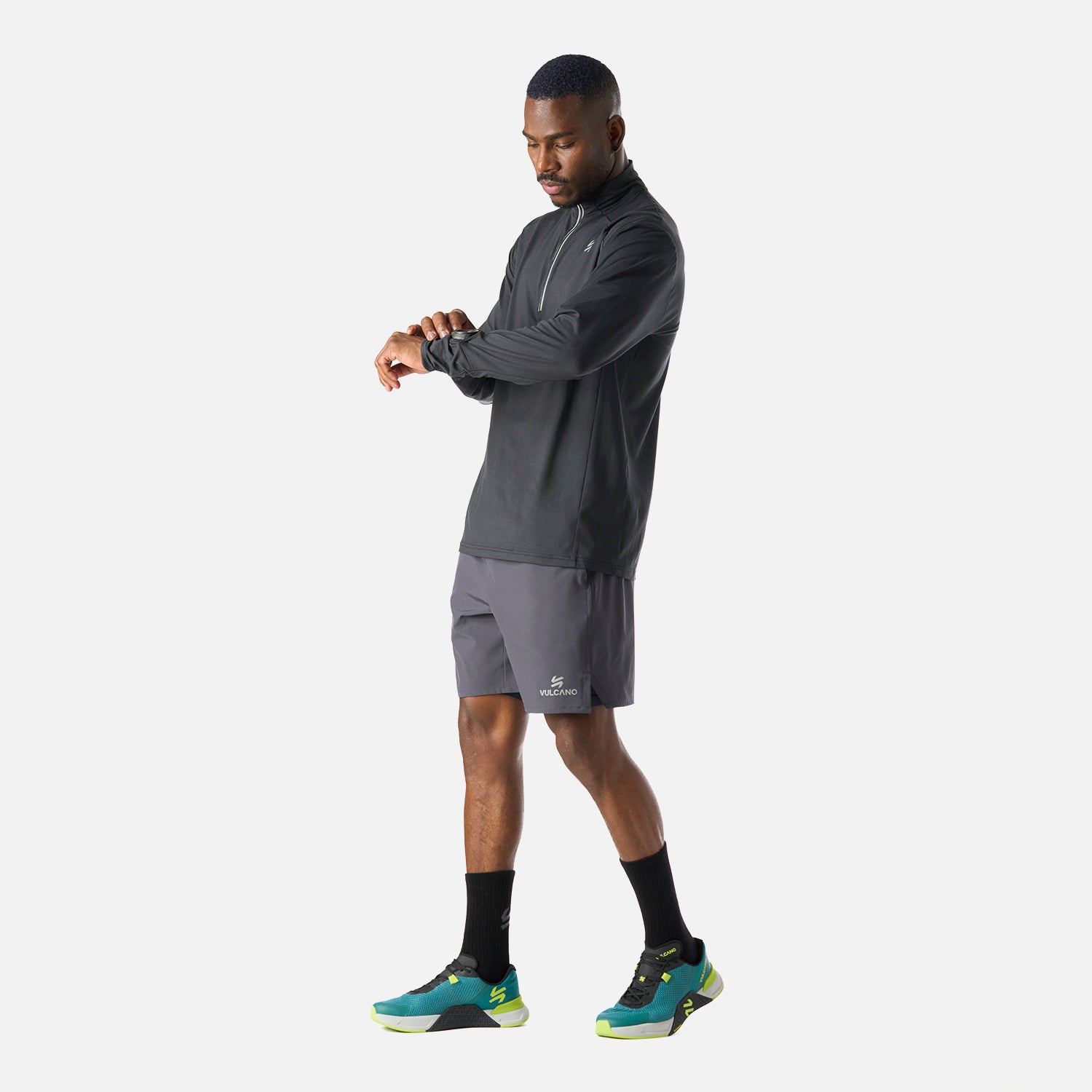 Polerón Hombre Tempo 1/4 Zip Midlayer Negro Vulcano combinado con short deportivo, perfecto para entrenamientos al aire libre o indoor.