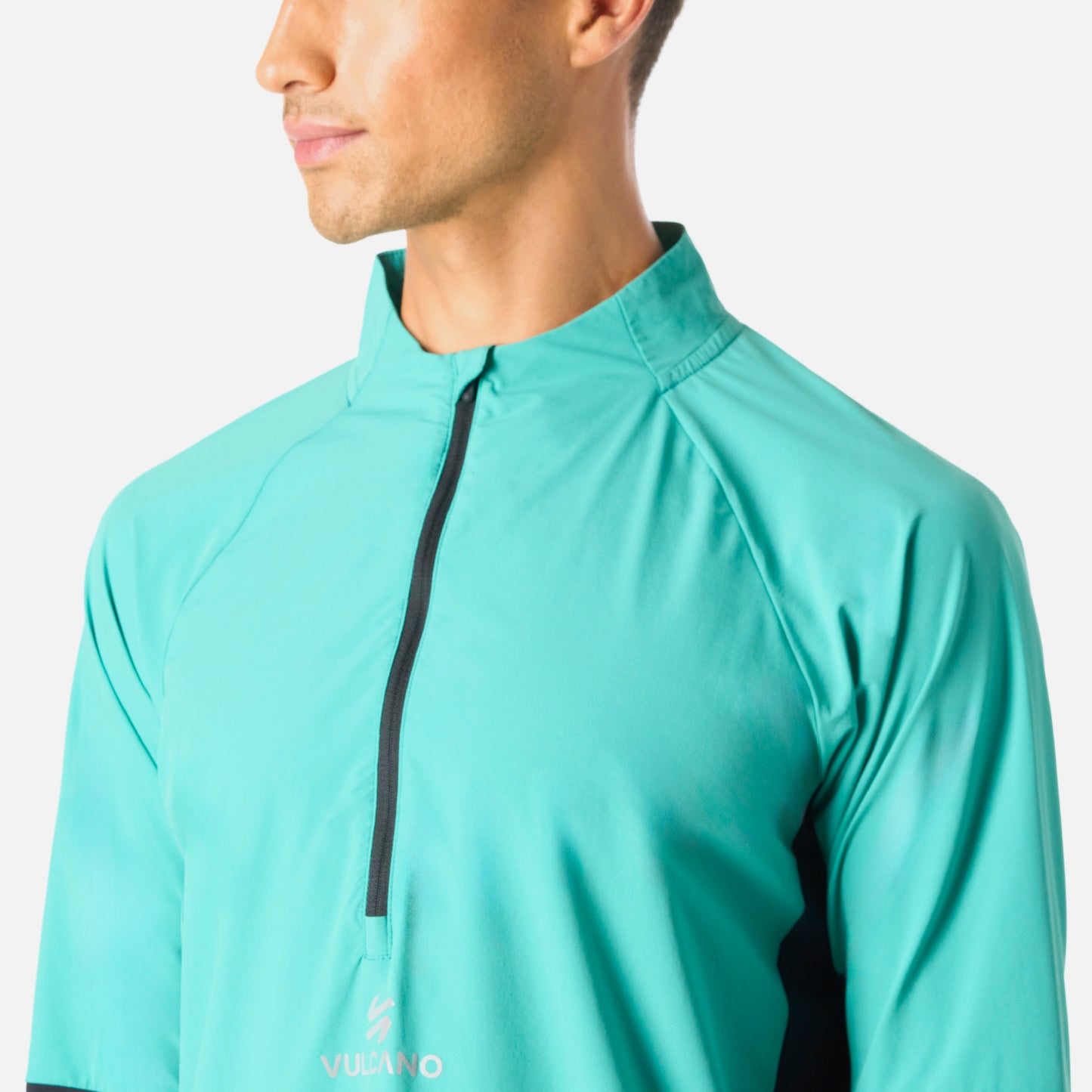 Detalle del cuello y cierre del Polerón Hombre Built To Move Pro 1/4 Zip Midlayer Turquesa Vulcano, con logo Vulcano al centro del pecho.