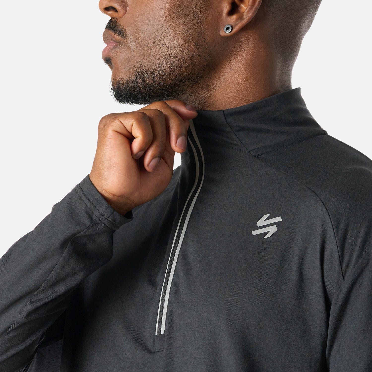 Detalle del cierre y logo en el pecho del Polerón Hombre Tempo 1/4 Zip Midlayer Negro Vulcano, con tela ligera y transpirable para invierno.