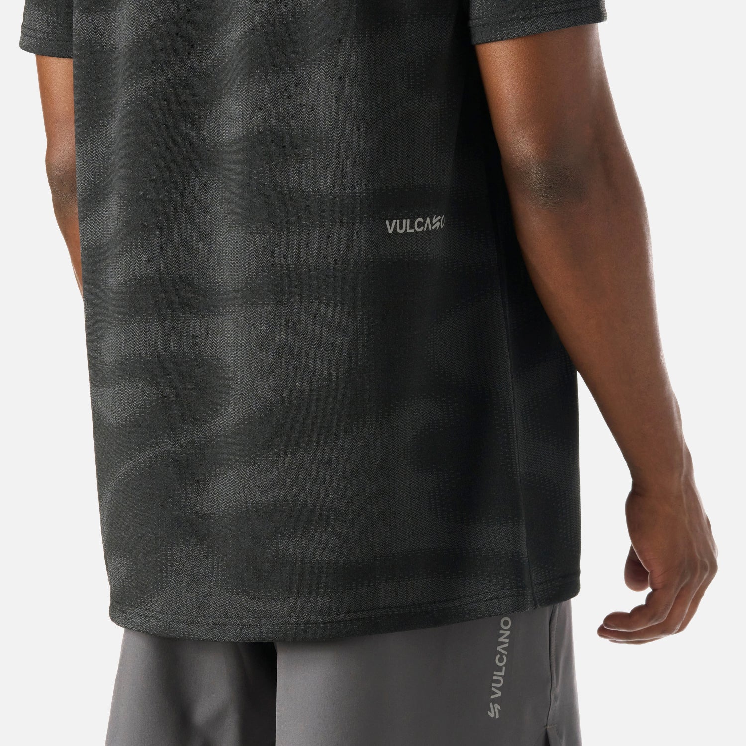 Detalle inferior de la Polera Hombre Built To Move Pro T-Shirt Negro Vulcano, con logo Vulcano y acabado premium en tela Q-Dry.
