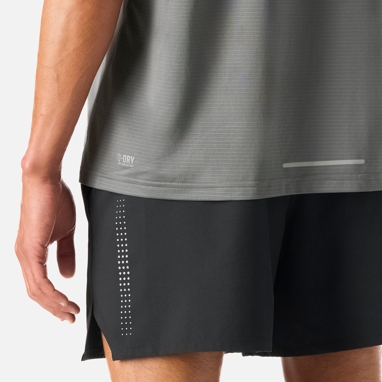 Detalle inferior de la Polera Hombre Tempo Advanced T-Shirt Gris Medio Vulcano mostrando tecnología Q-Dry y banda reflectante para mayor visibilidad.