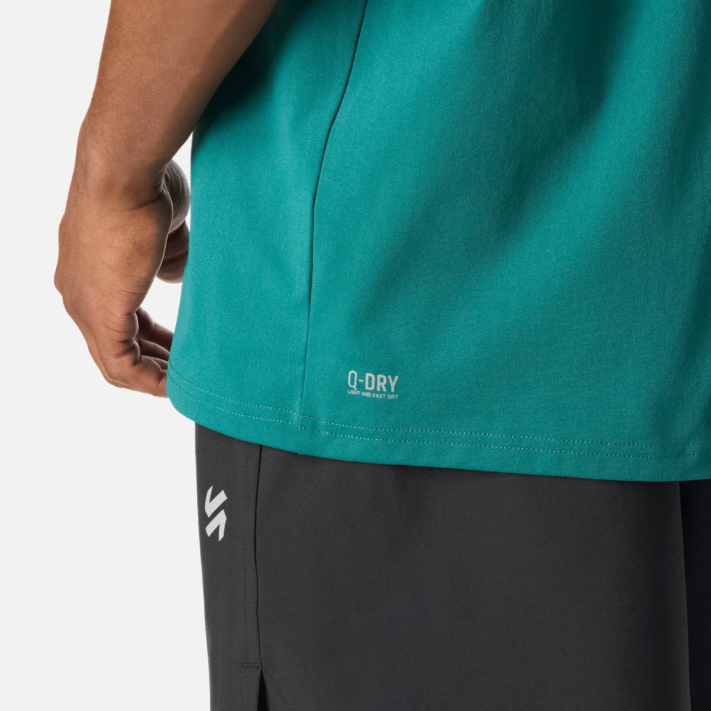 Detalle de la Polera Hombre Tempo T-Shirt Petroleo Vulcano con tecnología Q-Dry, mostrando el dobladillo inferior y parte del pantalón deportivo negro.