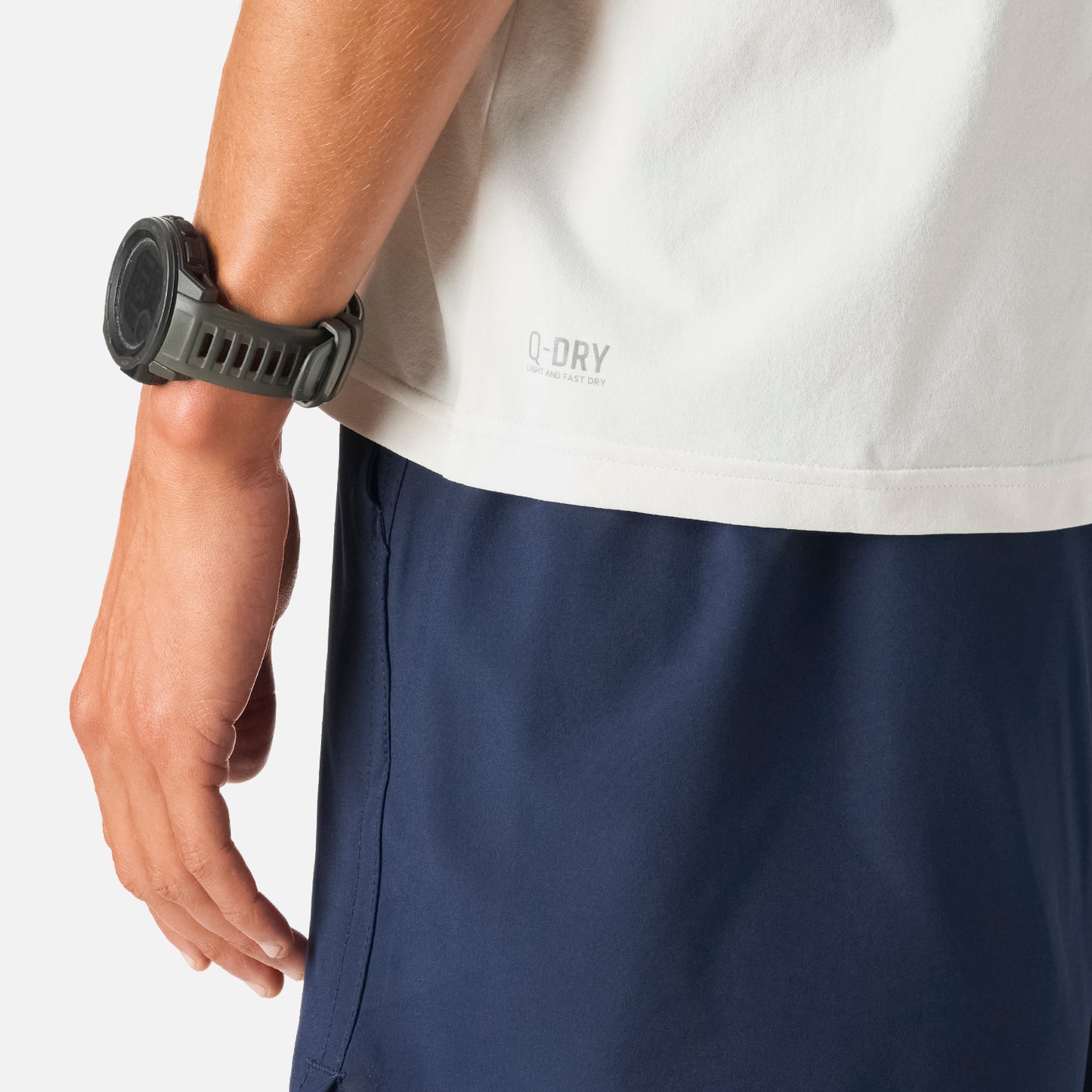 Detalle de la Polera Hombre Tempo T-Shirt Blanco Vulcano con tecnología Q-Dry, mostrando el dobladillo inferior y parte del pantalón deportivo negro.