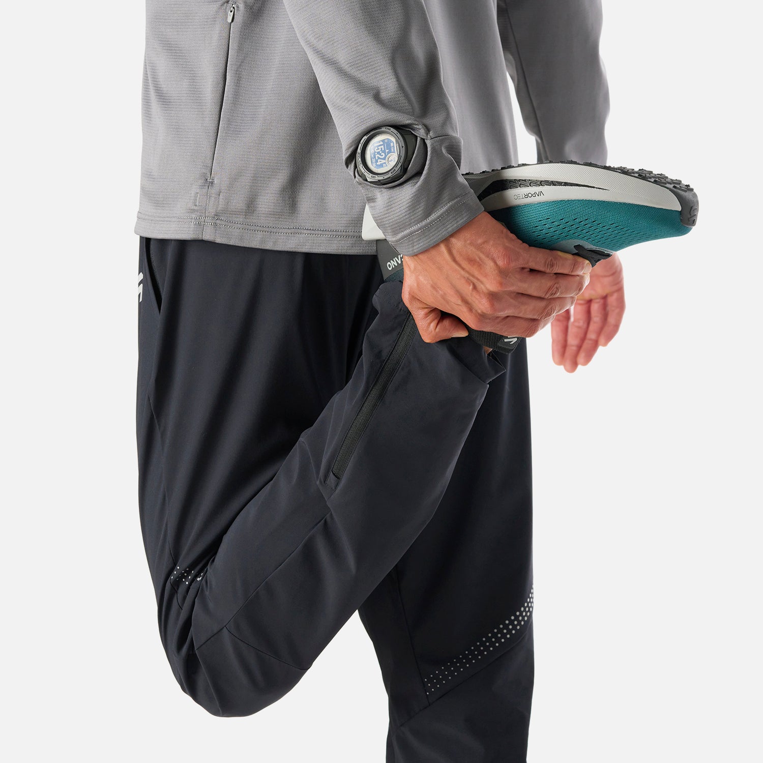 Polerón Hombre Built To Move 1/4 Zip Midlayer Gris Medio Vulcano usado durante estiramiento de pierna, ideal para running y entrenamiento funcional.