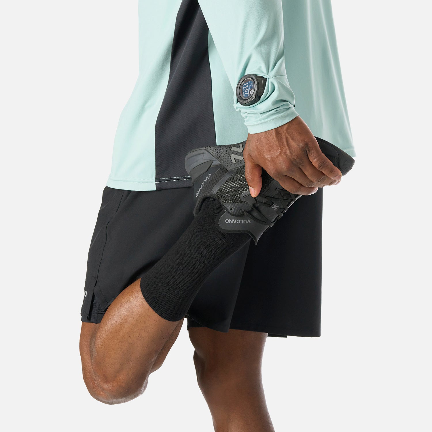 Polerón Hombre Tempo 1/4 Zip Midlayer Jade Vulcano combinado con short negro, mostrando flexibilidad y comodidad para rutinas de entrenamiento.