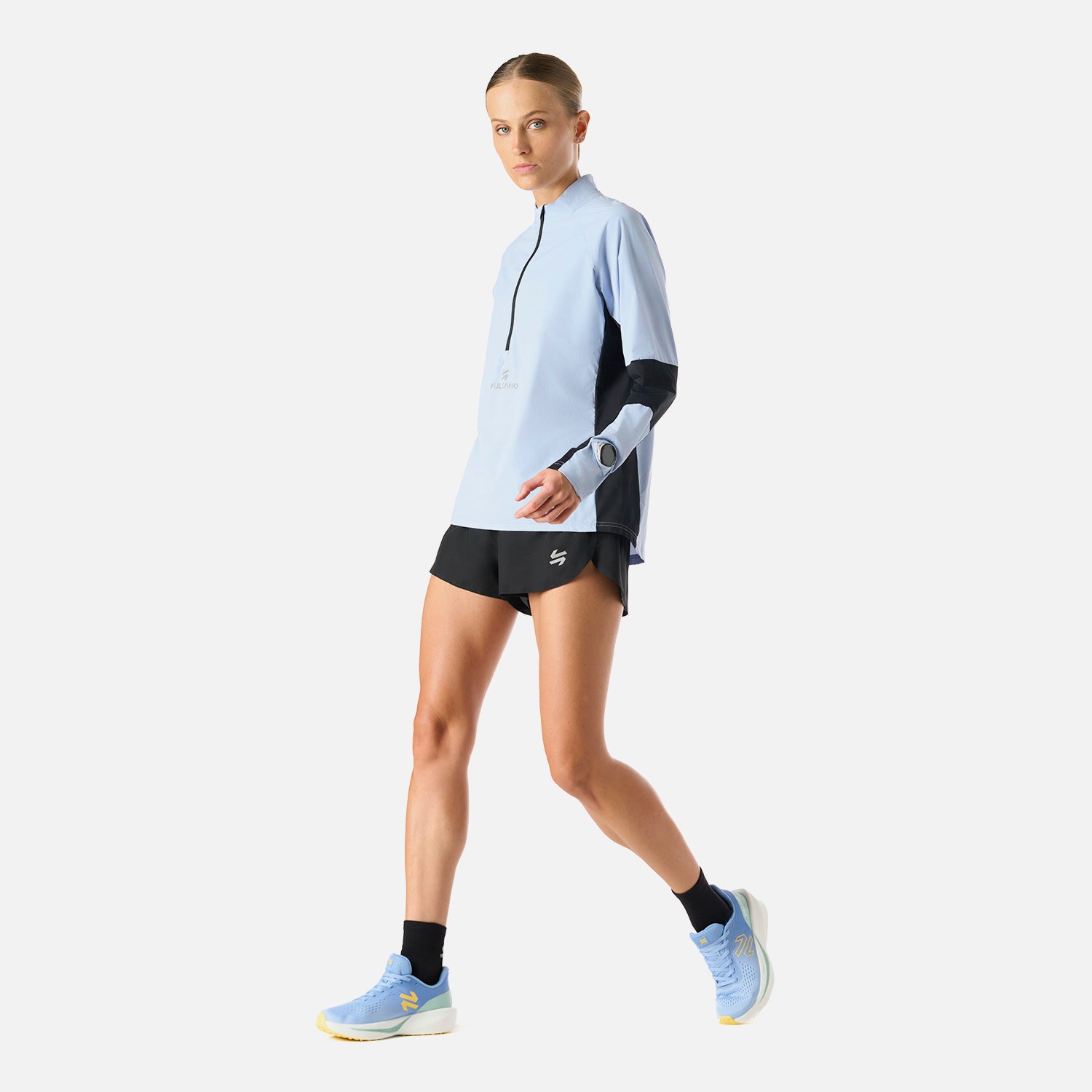 Polerón Mujer Built To Move Pro 1/4 Zip Midlayer Celeste Vulcano en acción, mostrando su diseño funcional para running y deportes de invierno.
