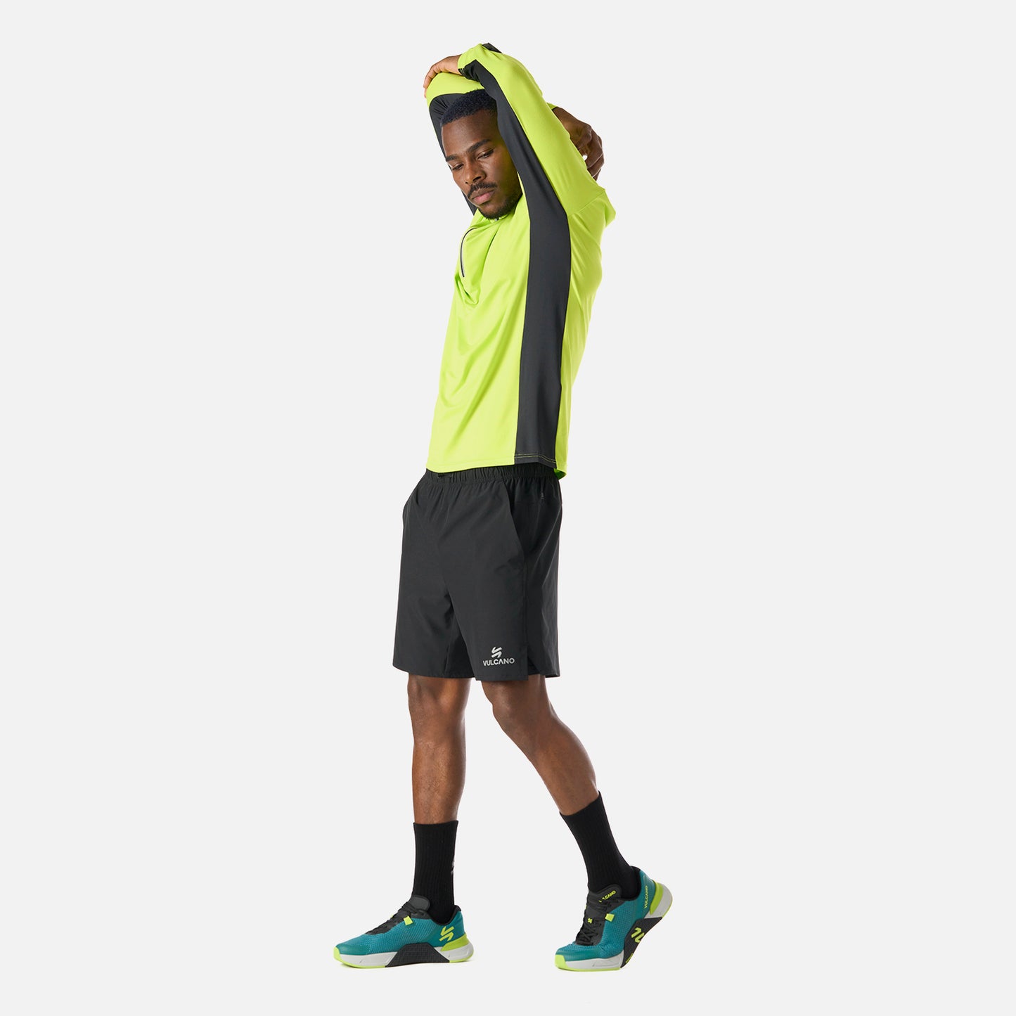 Hombre estirando con Polerón Tempo 1/4 Zip Midlayer Verde Lima Vulcano, prenda técnica para running, training y pádel.
