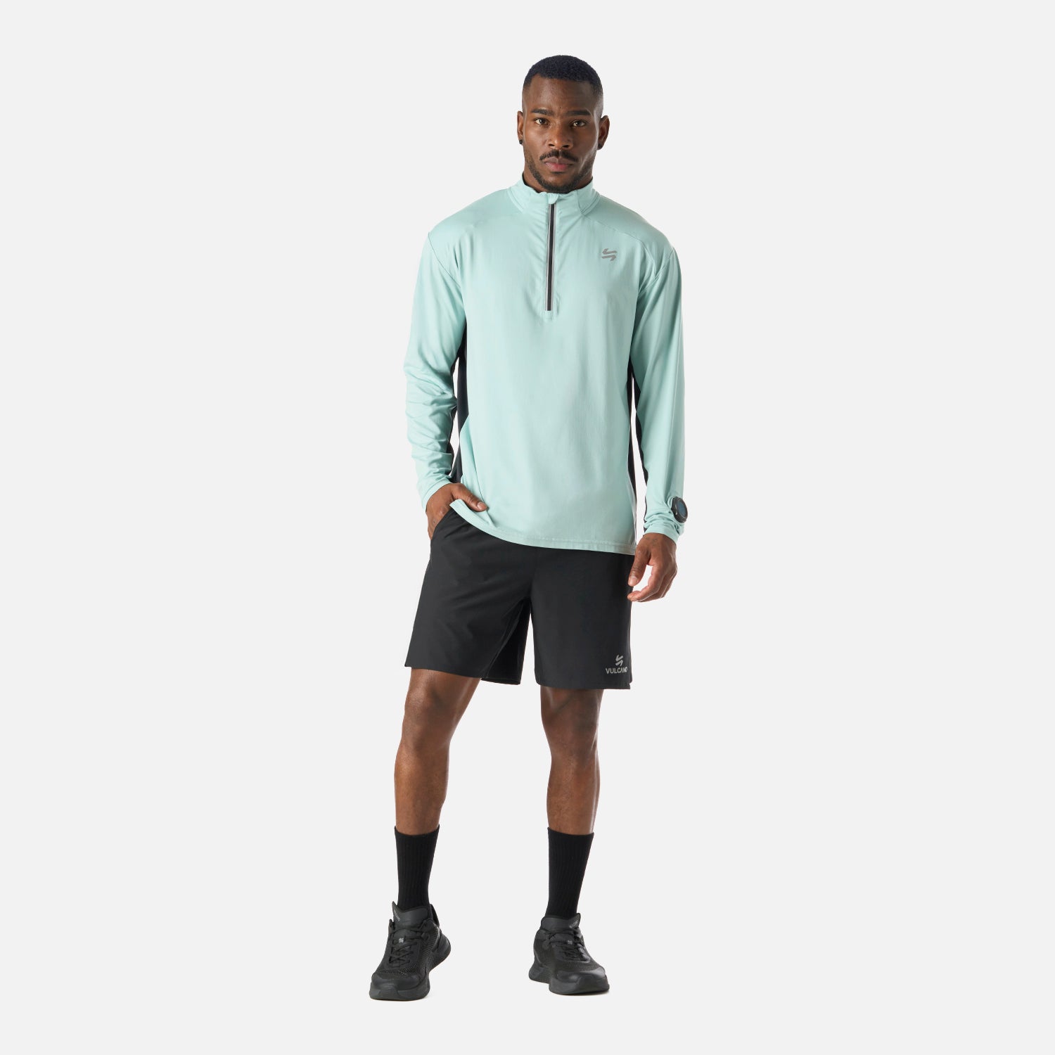 Conjunto deportivo con Polerón Hombre Tempo 1/4 Zip Midlayer Jade Vulcano y short negro, ideal para running, training y uso casual en invierno.