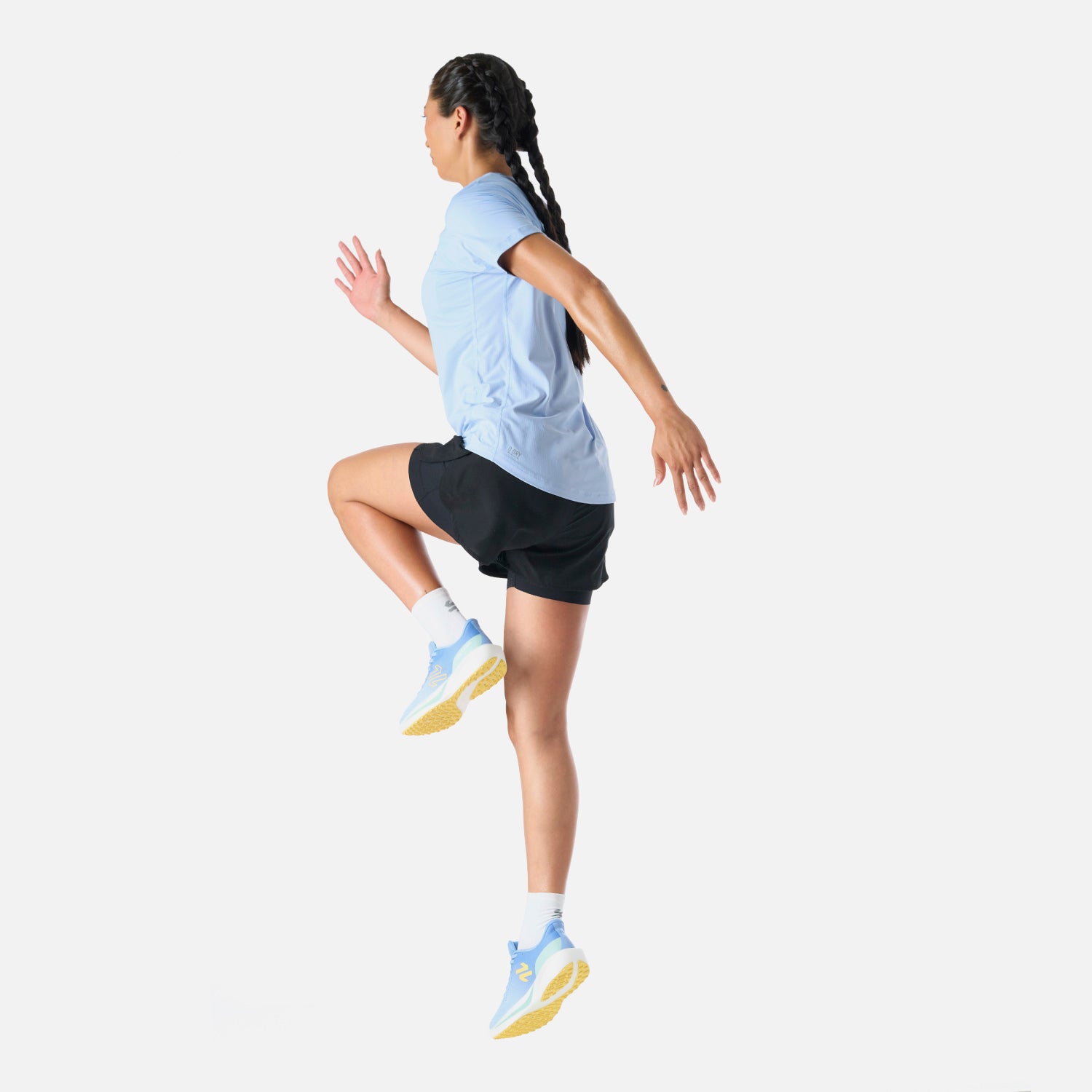 Polera Mujer Built To Move T-Shirt Celeste Vulcano en acción durante salto. Prenda ligera y flexible para alto rendimiento.